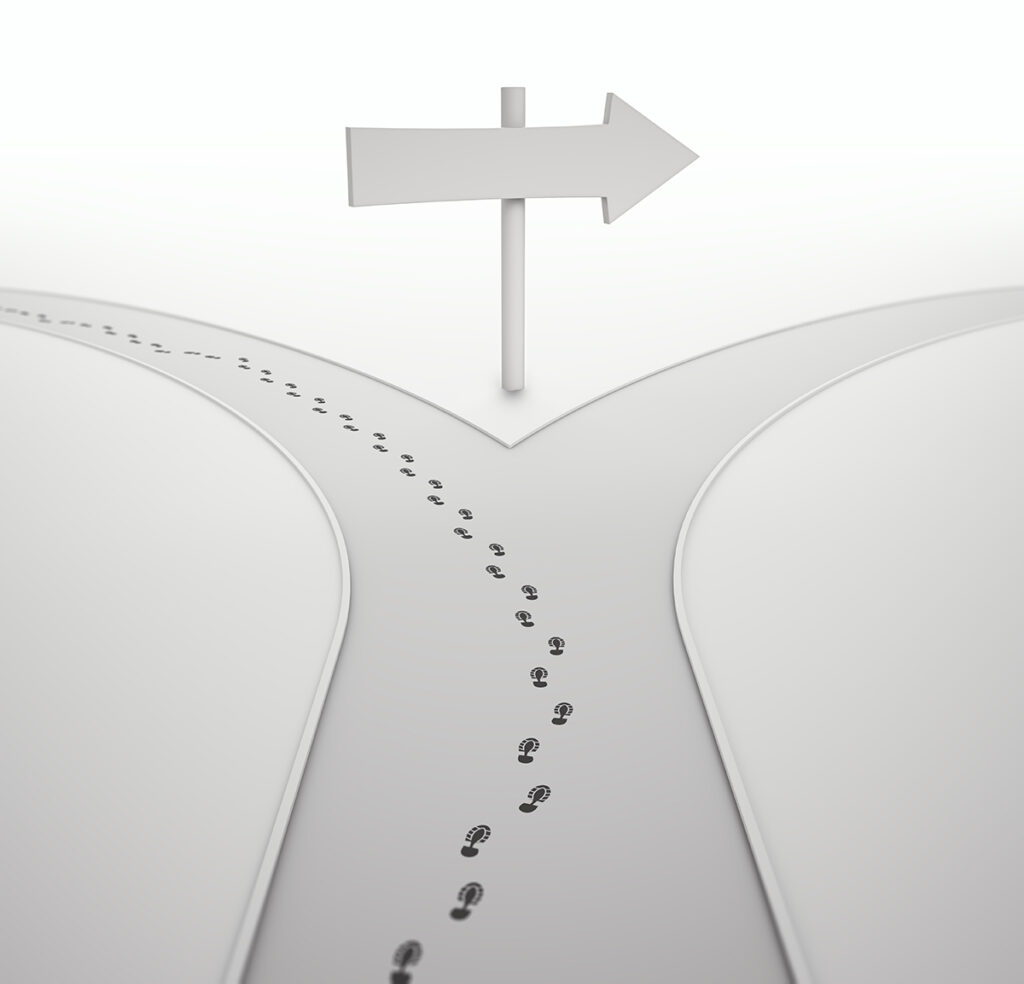 road diverging with footsteps going down one branch and a sign pointing down the other