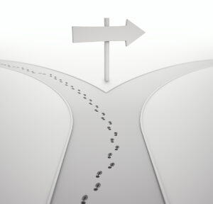 road diverging with footsteps going down one branch and a sign pointing down the other